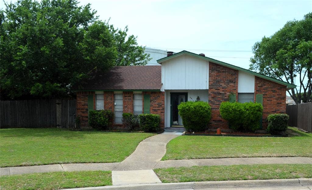 9615 Sophora Circle, Dallas, TX 75249 Brick exterior with white vertical siding accents and a brown shingle roof