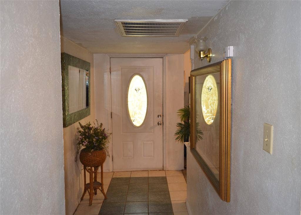 9615 Sophora Circle, Dallas, TX 75249 Entryway featuring a white paneled door with an oval glass insert, tile flooring, and textured wall finishes