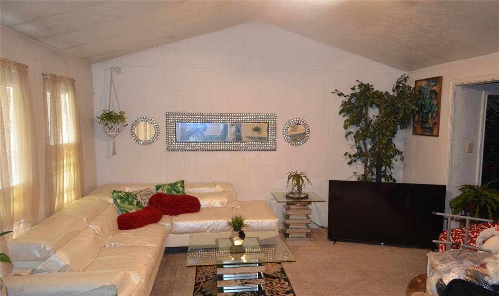 9615 Sophora Circle, Dallas, TX 75249 Vaulted ceiling living area featuring a large window, light-toned wall finishes, and carpet flooring
