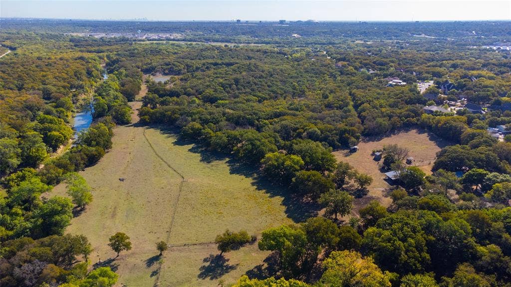 8601 Lowery Road, Fort Worth, TX 76120 Expansive acreage featuring abundant mature trees, a natural watercourse, and established open fields