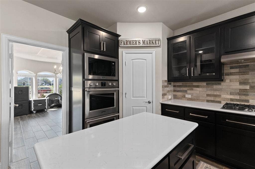 800 Beckington Drive, Shady Shores, TX 76208 Gourmet kitchen featuring dark wood cabinetry, stainless steel appliances, a white island countertop, and a tiled backsplash