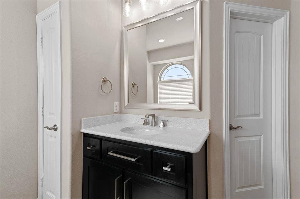 800 Beckington Drive, Shady Shores, TX 76208 Bathroom vanity featuring a dark wood-finish cabinet with silver hardware, an integrated white sink, and a light-colored countertop