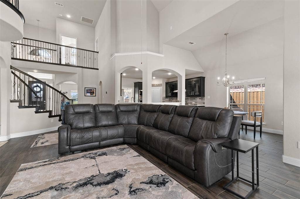 800 Beckington Drive, Shady Shores, TX 76208 Two-story living area featuring wood-finish flooring, a grand staircase with wrought iron balusters, arched doorways, a high ceiling, and a dining space with a chandelier