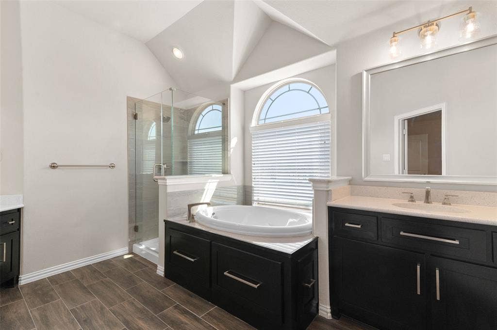 800 Beckington Drive, Shady Shores, TX 76208 Secondary primary Bathroom featuring a built-in soaking tub, a glass-enclosed shower, dual dark wood vanities with light countertops, and wood-finish flooring