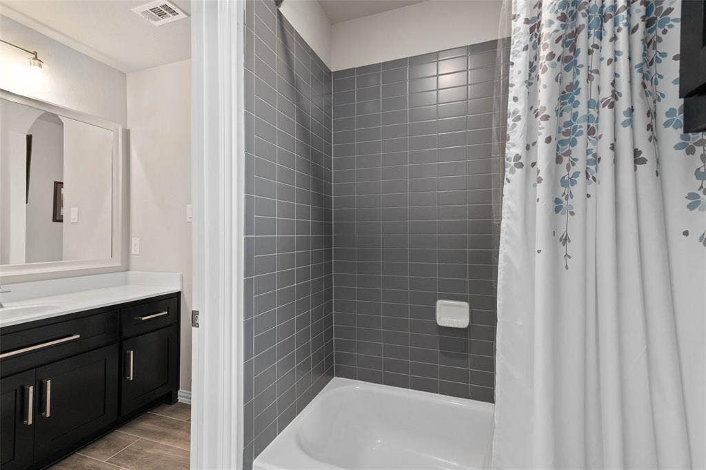 800 Beckington Drive, Shady Shores, TX 76208 Bathroom featuring a white tub, gray subway tile surround, dark wood-finish vanity with a white countertop, and a framed mirror