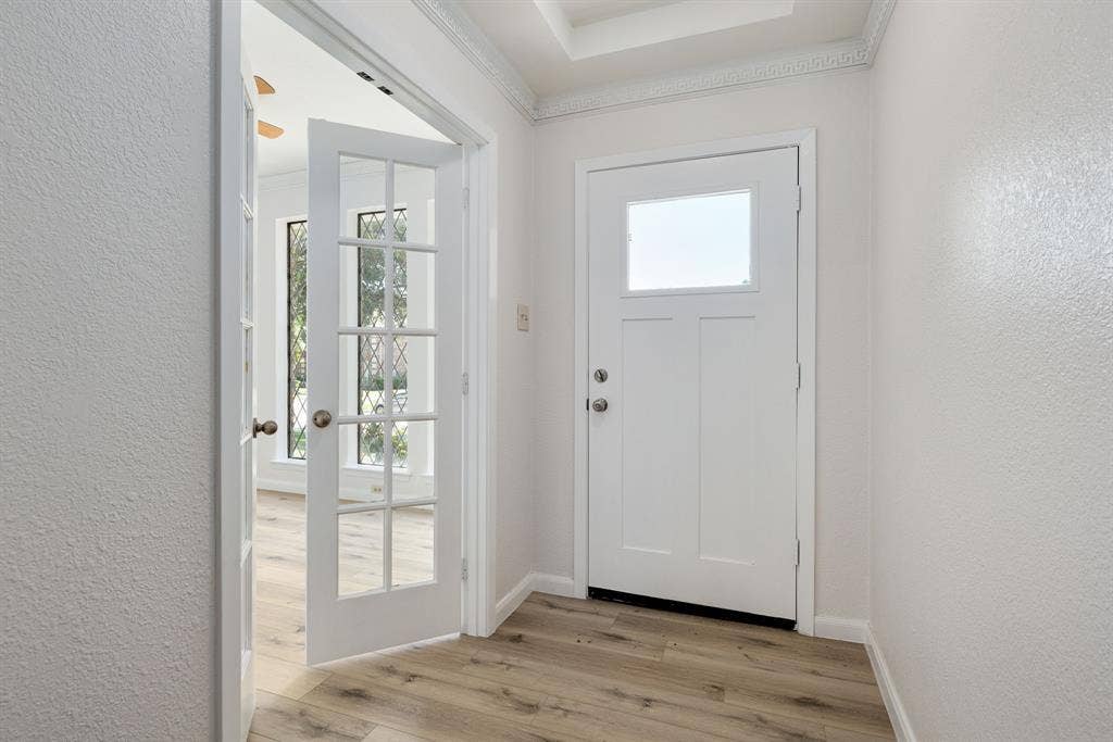 3406 Windridge Drive, Garland, TX 75043 Entryway featuring light wood-finish flooring, a white front door with a square window, and decorative crown molding