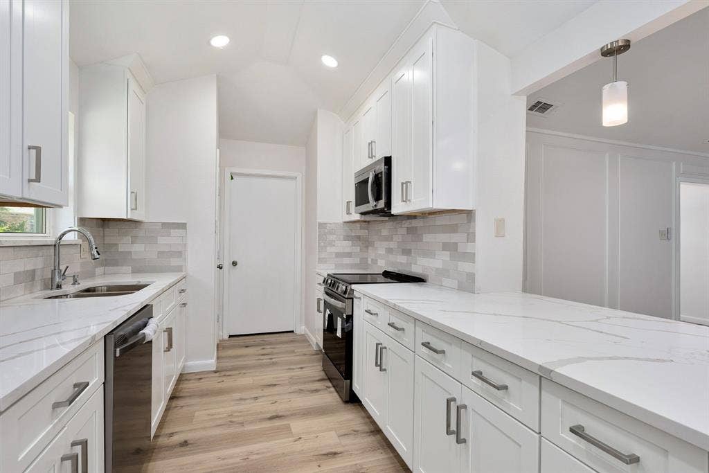 3406 Windridge Drive, Garland, TX 75043 Contemporary kitchen with white shaker cabinetry, light-toned wood-finish flooring, and a subway tile backsplash