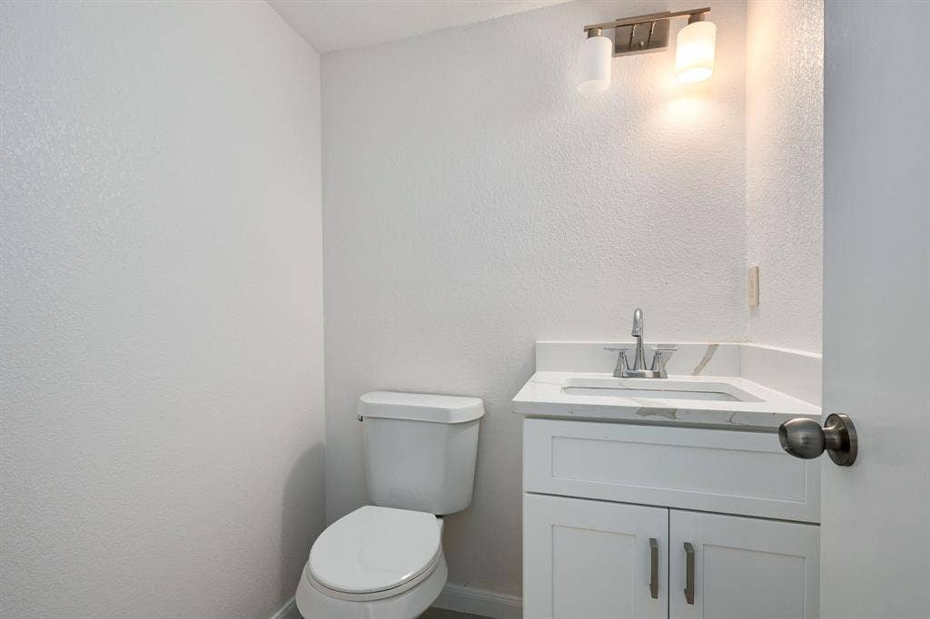 3406 Windridge Drive, Garland, TX 75043 Modern bathroom vanity featuring a white cabinet, integrated sink, and stone-finish countertop