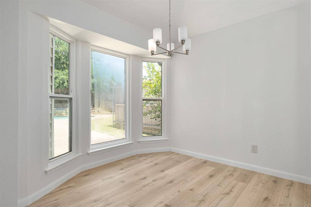 3406 Windridge Drive, Garland, TX 75043 Bay window with white trim, wood-finish flooring, white walls, and a contemporary chandelier