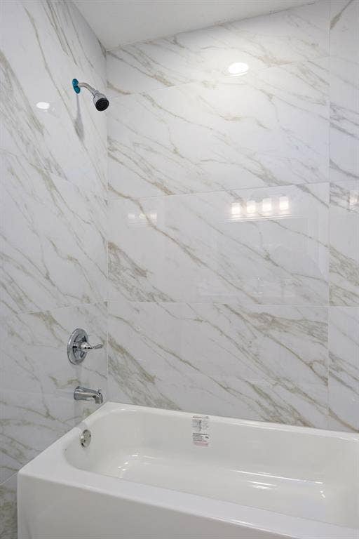 3406 Windridge Drive, Garland, TX 75043 Shower and tub combination featuring white marble-patterned wall tiling and chrome fixtures