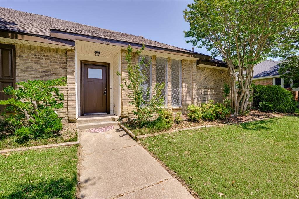 3406 Windridge Drive, Garland, TX 75043 Brick exterior with an entryway featuring a brown door with a window pane
