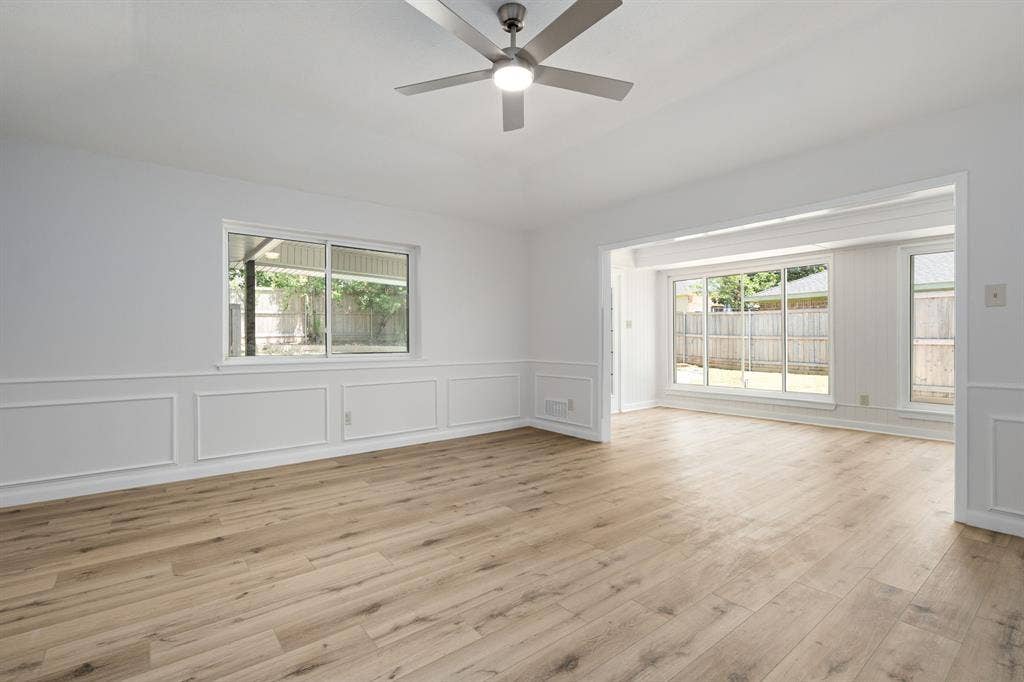 3406 Windridge Drive, Garland, TX 75043 Open living area featuring light wood-finish flooring, white paneling, and a modern ceiling fan