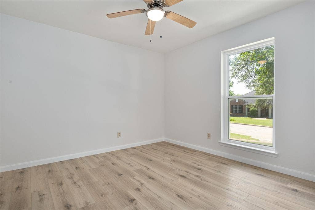 3406 Windridge Drive, Garland, TX 75043 Spacious room featuring wood-finish flooring, crisp white walls, and a large window