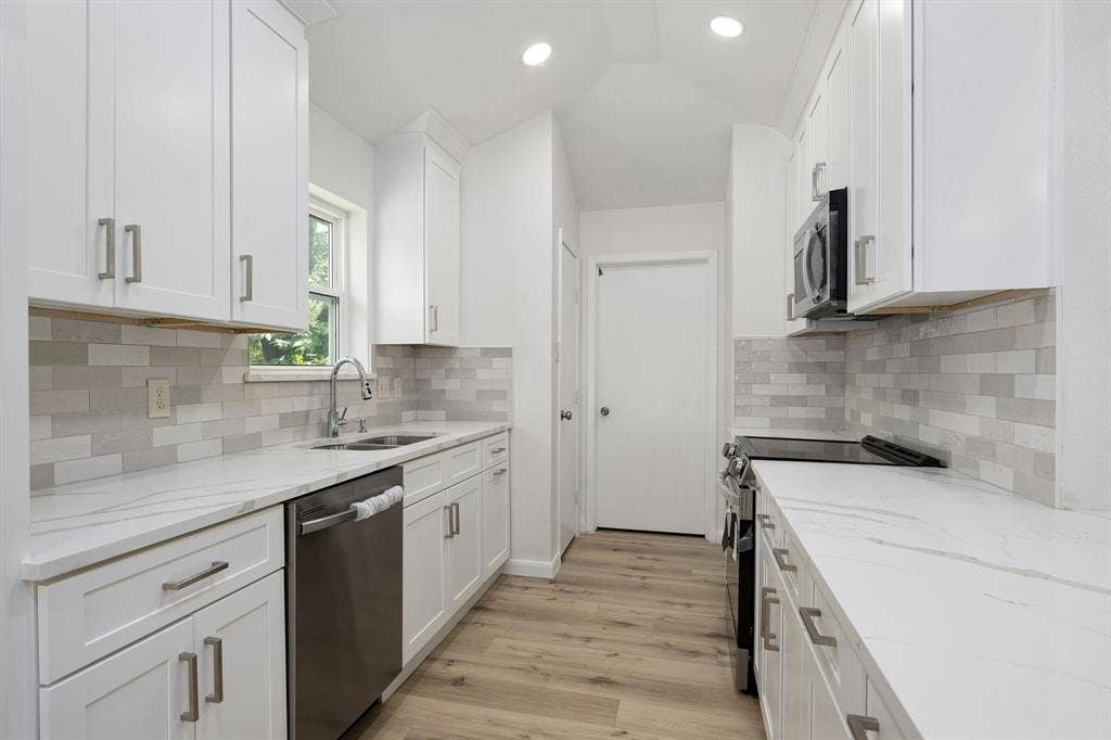 3406 Windridge Drive, Garland, TX 75043 Modern kitchen featuring white shaker cabinetry, quartz countertops, a subway tile backsplash, stainless steel appliances, and wood-finish flooring