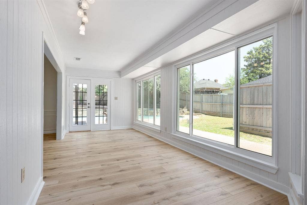 3406 Windridge Drive, Garland, TX 75043 Bright interior space featuring wood-finish flooring, full-height paneling, and an array of large windows