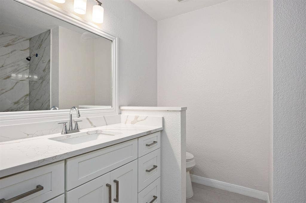 3406 Windridge Drive, Garland, TX 75043 Bathroom vanity featuring a white countertop with integrated sink, brushed nickel faucet, and white cabinetry with coordinating hardware