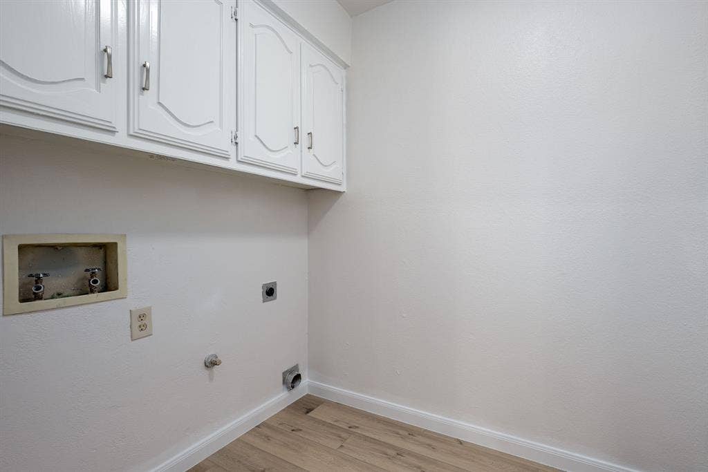 3406 Windridge Drive, Garland, TX 75043 Laundry area featuring white cabinetry, light wood-finish flooring, and white baseboards