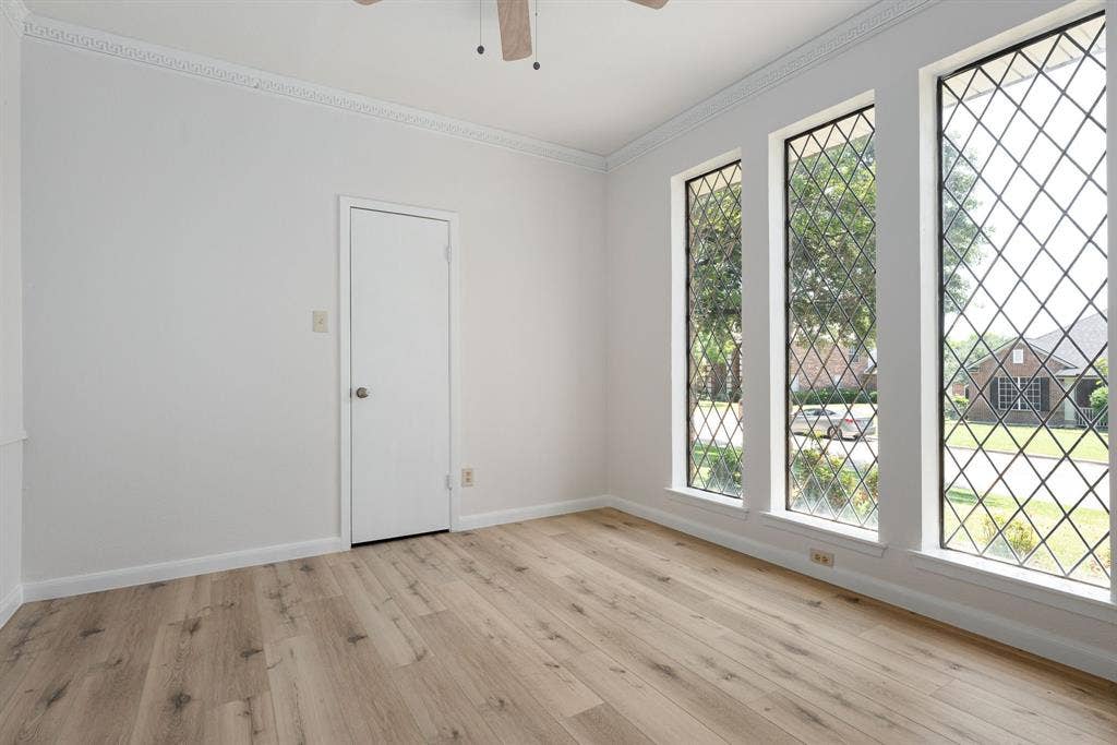 3406 Windridge Drive, Garland, TX 75043 Room featuring three tall windows with diamond-patterned grilles, wood-finish flooring, a white door, and crown molding