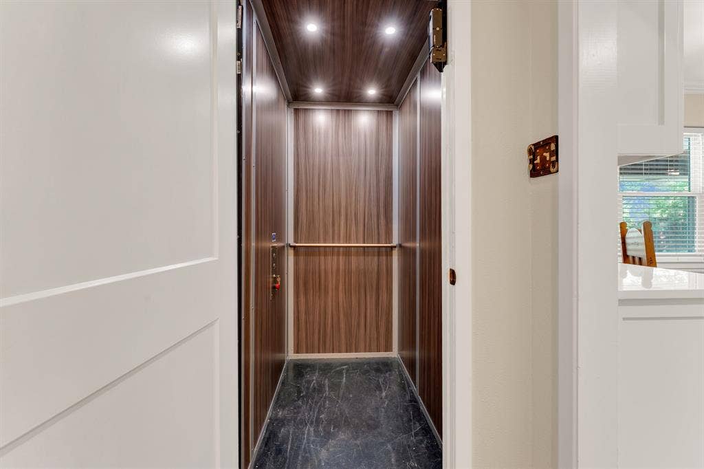 3908 Wildwood, Euless, TX 76040 Interior residential elevator featuring wood-finish paneling, recessed ceiling lighting, and a dark stone-finish floor