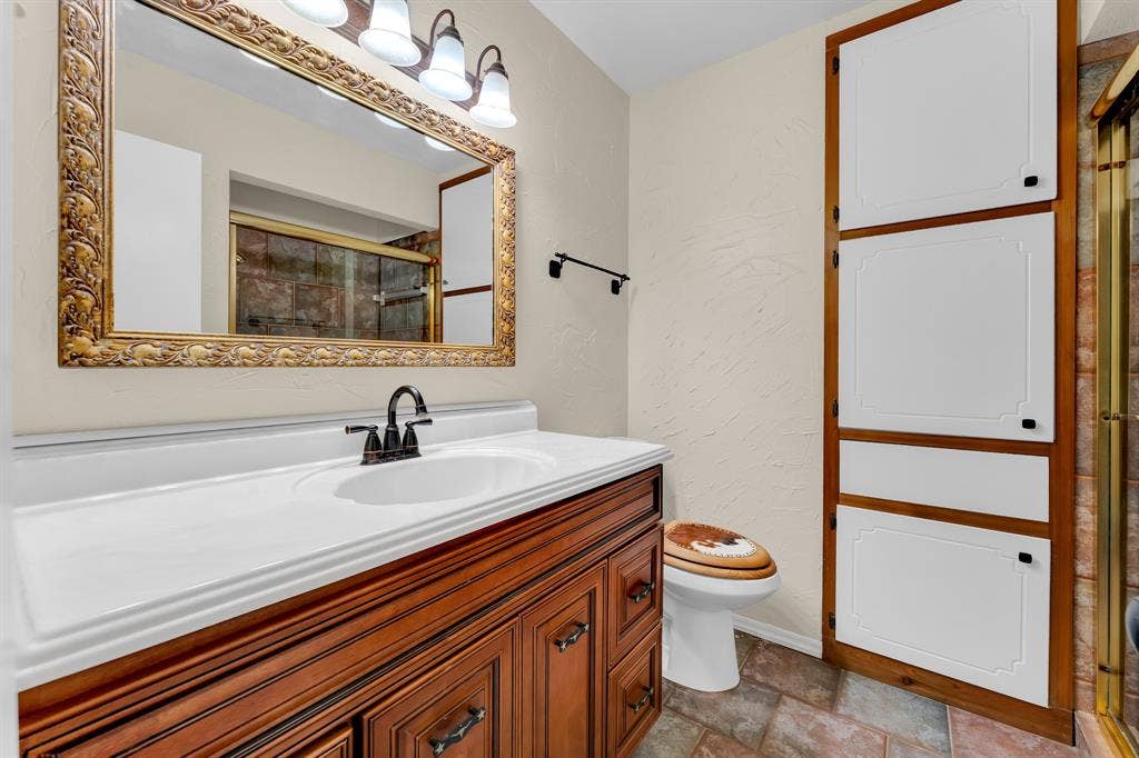 3908 Wildwood, Euless, TX 76040 Wood-finish vanity with an integrated white sink and dark bronze faucet