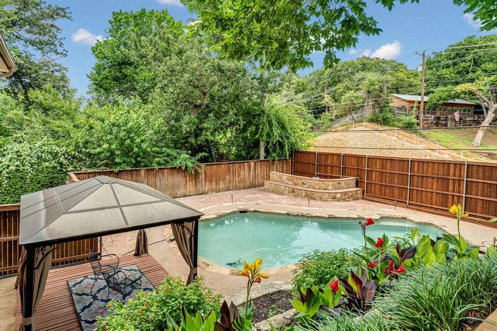 3908 Wildwood, Euless, TX 76040 Backyard oasis featuring a swimming pool with integrated stone steps, a wood-finish deck with a built-in gazebo, and mature landscaping