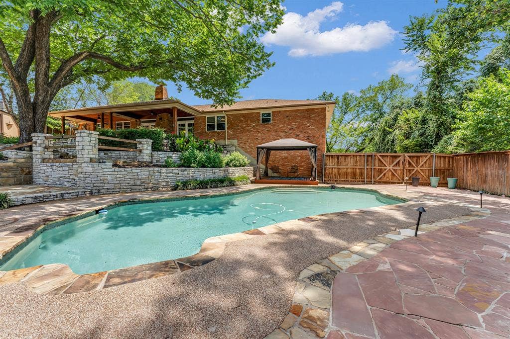 3908 Wildwood, Euless, TX 76040 Curved swimming pool with flagstone and aggregate coping, complemented by a multi-level stone retaining wall
