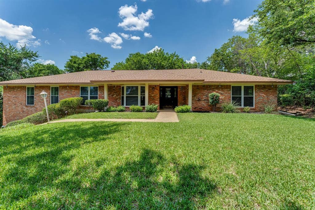 3908 Wildwood, Euless, TX 76040 Brick exterior with a prominent front walkway, a brown shingle roof, mature landscaping, and an integrated porch entry