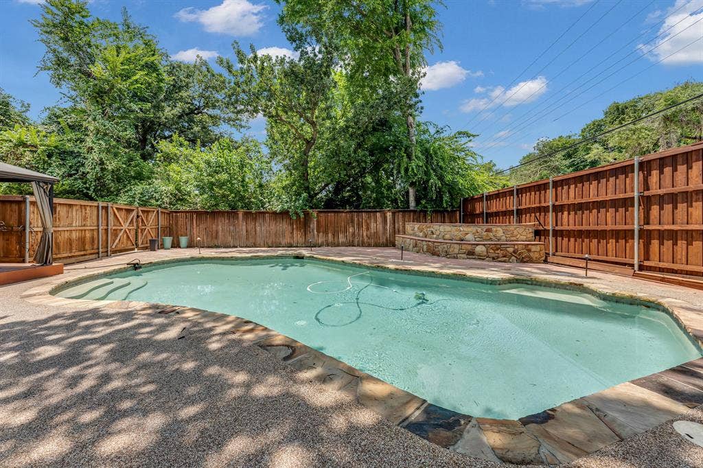 3908 Wildwood, Euless, TX 76040 In-ground swimming pool with flagstone coping and an aggregate concrete surround