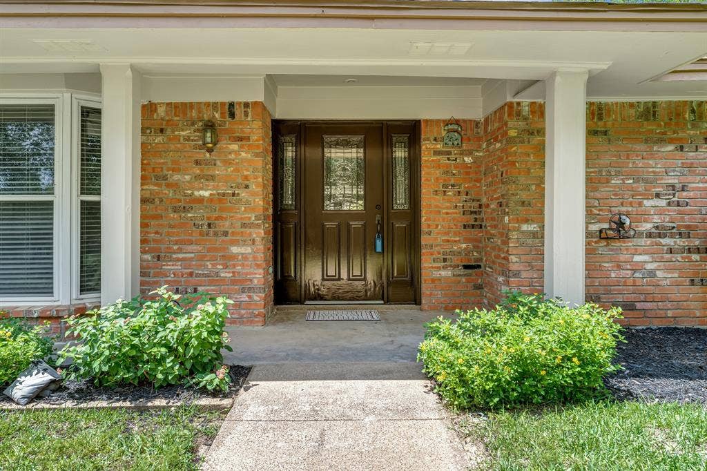 3908 Wildwood, Euless, TX 76040 Inviting brick facade with a covered entry, featuring a paneled front door with decorative glass inserts and side lights