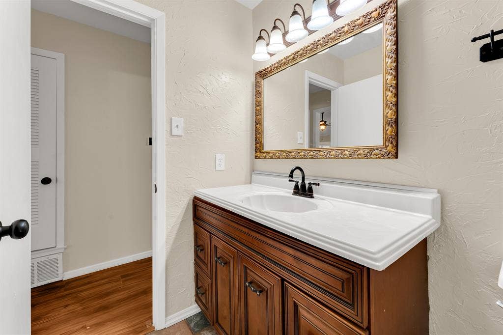 3908 Wildwood, Euless, TX 76040 Bathroom vanity featuring a dark wood cabinet, white countertop with integrated sink, and a black faucet