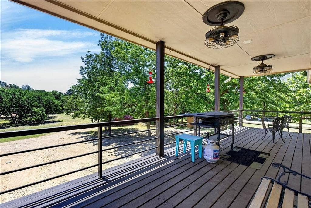 11591 Farm Market 59, Athens, TX 75751 Spacious outdoor deck and back porch balcony featuring a black metal railing overlooking a tree-lined serene landscape.