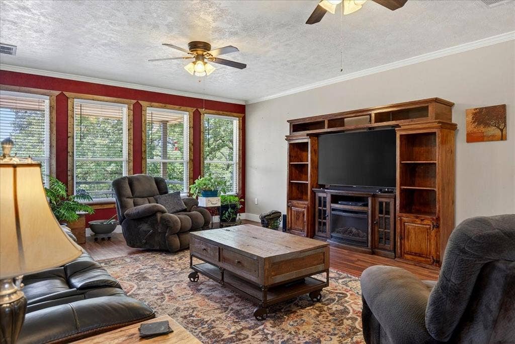 11591 Farm Market 59, Athens, TX 75751 Living area featuring a multi-panel window wall with wood trim and red accent wall, ceiling fans, wood laminate floors throughout. Open Concept floor plan.