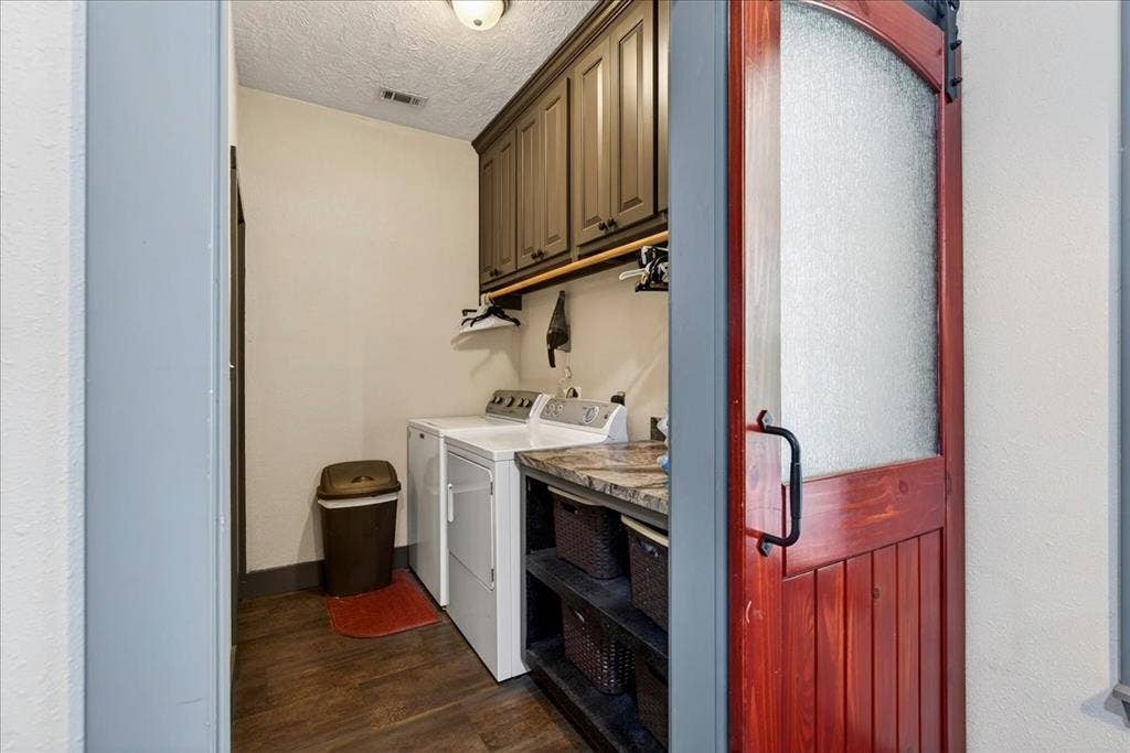 11591 Farm Market 59, Athens, TX 75751 Laundry area featuring a rustic wood-finish barn door with frosted glass, wood-finish flooring, built-in upper cabinetry, and a stone-finish countertop with open shelving below. SPECIAL FEATURE: staircase leading down to the basement is in the most PERFECT out-of-the-way place - right here in the laundry room.