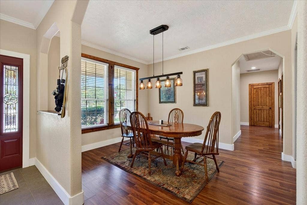 11591 Farm Market 59, Athens, TX 75751 Dining area featuring wood-finish flooring, a linear chandelier, and expansive windows with wooden trim, open to the living-office-kitchen.