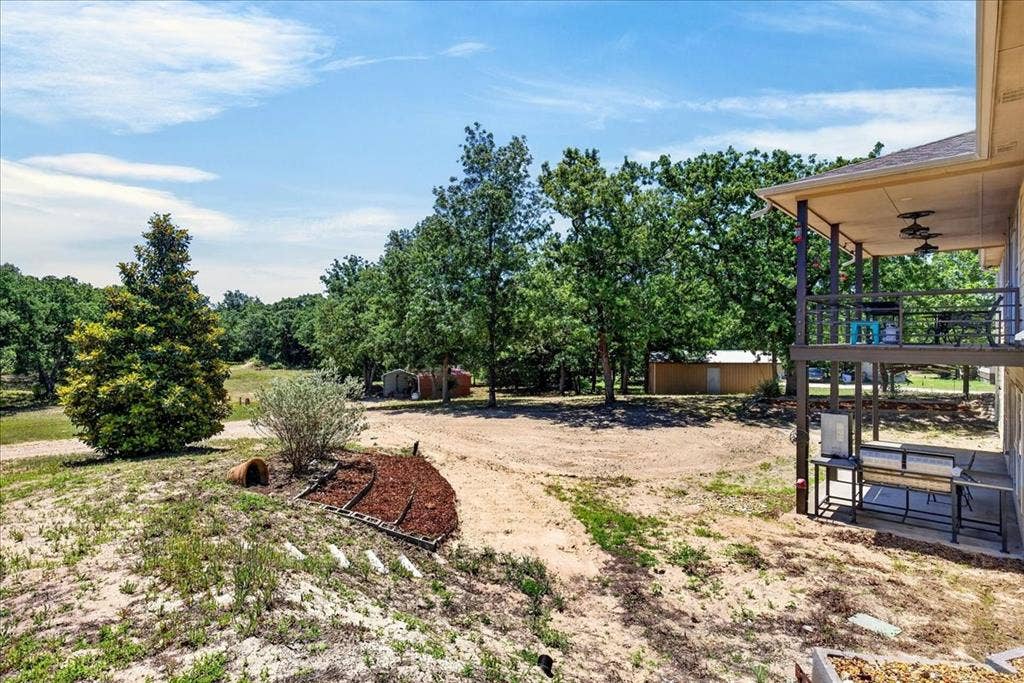 11591 Farm Market 59, Athens, TX 75751 Expansive outdoor area featuring a two-story covered patio, mature trees, and a detached outbuilding