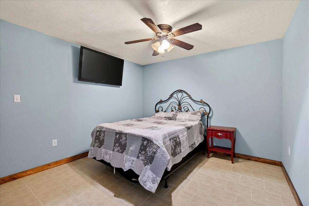 11591 Farm Market 59, Athens, TX 75751 5th Bedroom in Basement level with Light blue painted walls featuring a ceiling fan with light fixture and tile flooring and closet. SPECIAL FEATURE: this room is also an EMERGENCY SAFE ROOM because of the completely concreted walls and no window.