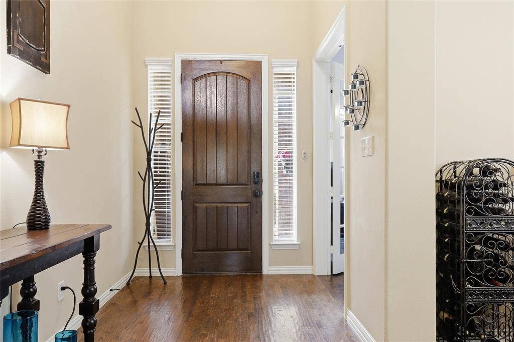 6905 Denali Drive, McKinney, TX 75070 Front entry featuring a solid wood arched door with sidelight windows, wood-finish flooring, and neutral wall tones