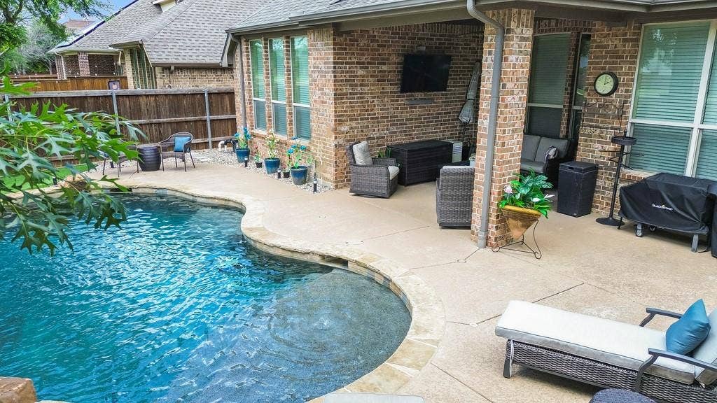 6905 Denali Drive, McKinney, TX 75070 Curved in-ground pool with stone coping and an expansive concrete patio
