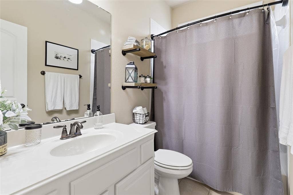 6905 Denali Drive, McKinney, TX 75070 Bathroom featuring a white vanity with an integrated sink, brushed bronze faucet, and a large wall-mounted mirror