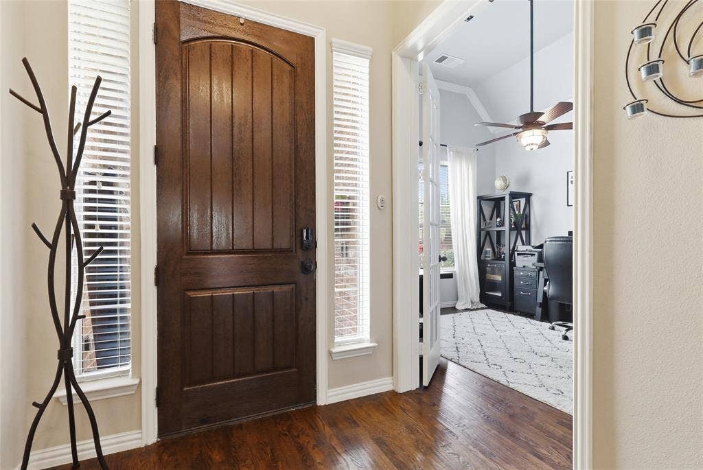 6905 Denali Drive, McKinney, TX 75070 Rich wood-finish flooring complements the substantial wood entry door with side light windows
