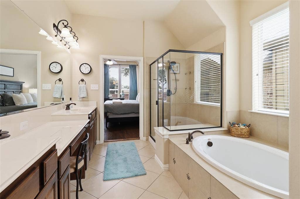 6905 Denali Drive, McKinney, TX 75070 Spacious bathroom featuring a built-in soaking tub, a glass-enclosed shower, and a double vanity with an integrated mirror