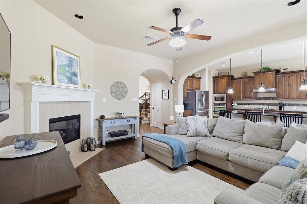 6905 Denali Drive, McKinney, TX 75070 Open-concept living area featuring a fireplace with a white mantel, wood-finish flooring, and recessed lighting