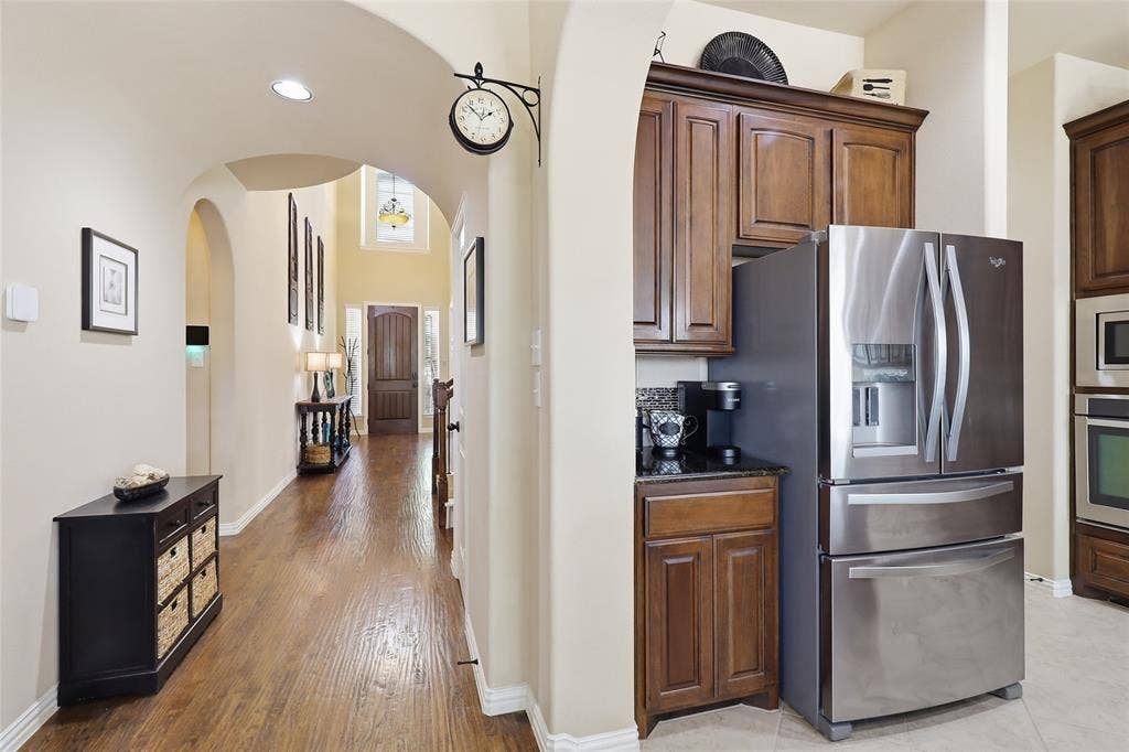 6905 Denali Drive, McKinney, TX 75070 Kitchen area featuring stainless steel French door refrigerator, dark wood-finish cabinetry, and dark countertop
