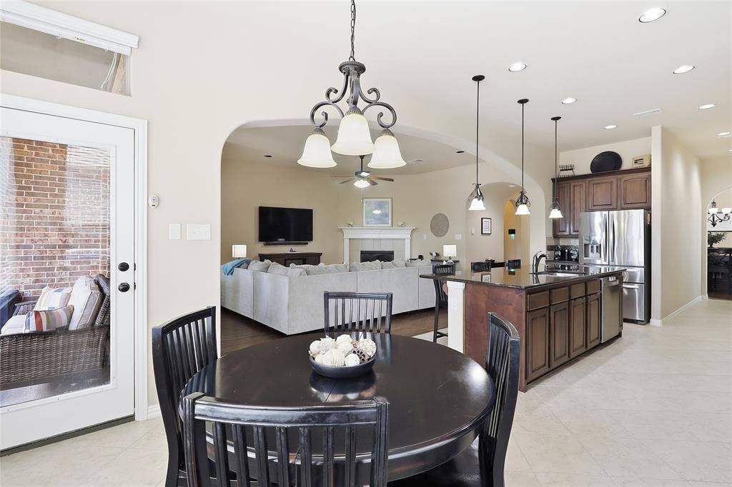 6905 Denali Drive, McKinney, TX 75070 Open-concept living area with a kitchen island, pendant lighting, stainless steel appliances, and a dining area featuring a chandelier