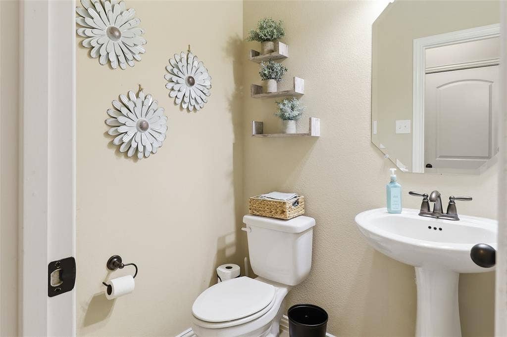 6905 Denali Drive, McKinney, TX 75070 Pedestal sink with a two-handle faucet and an octagonal wall mirror