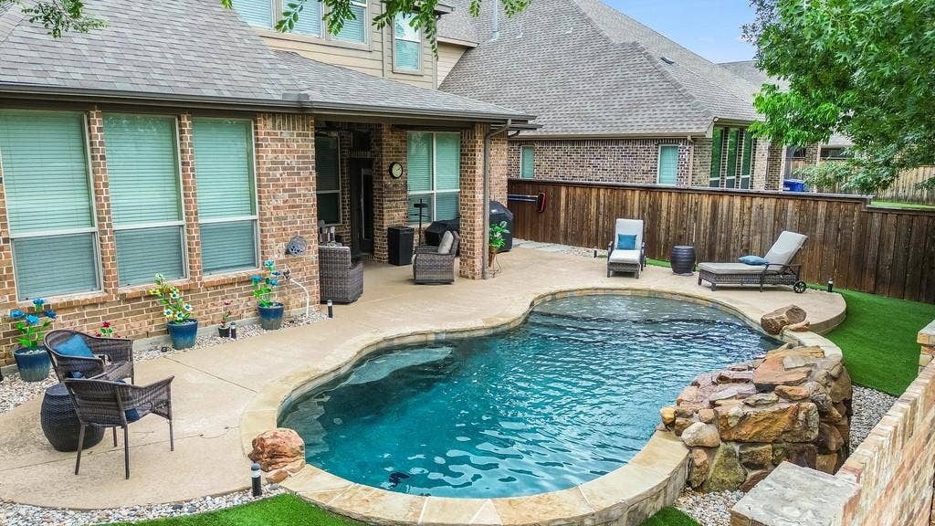 6905 Denali Drive, McKinney, TX 75070 Backyard featuring a freeform swimming pool with a stone waterfall feature