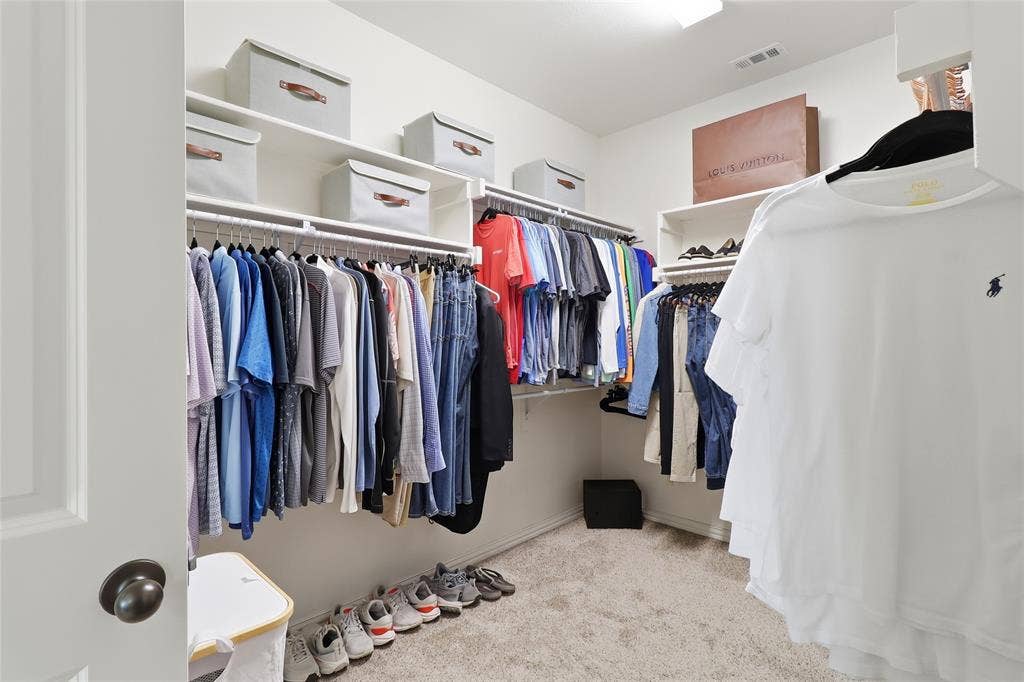 6905 Denali Drive, McKinney, TX 75070 Walk-in closet with carpet flooring, extensive shelving, and multiple hanging rods for organization