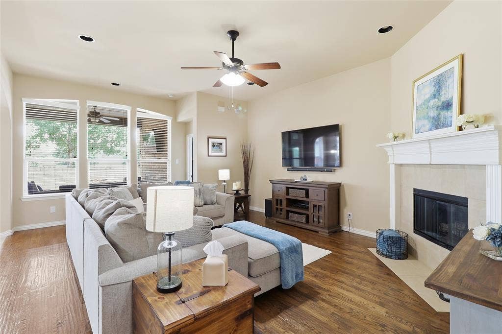 6905 Denali Drive, McKinney, TX 75070 Living room featuring wood-finish flooring, a fireplace with a light-colored tile surround and white mantel, a ceiling fan, and recessed lighting