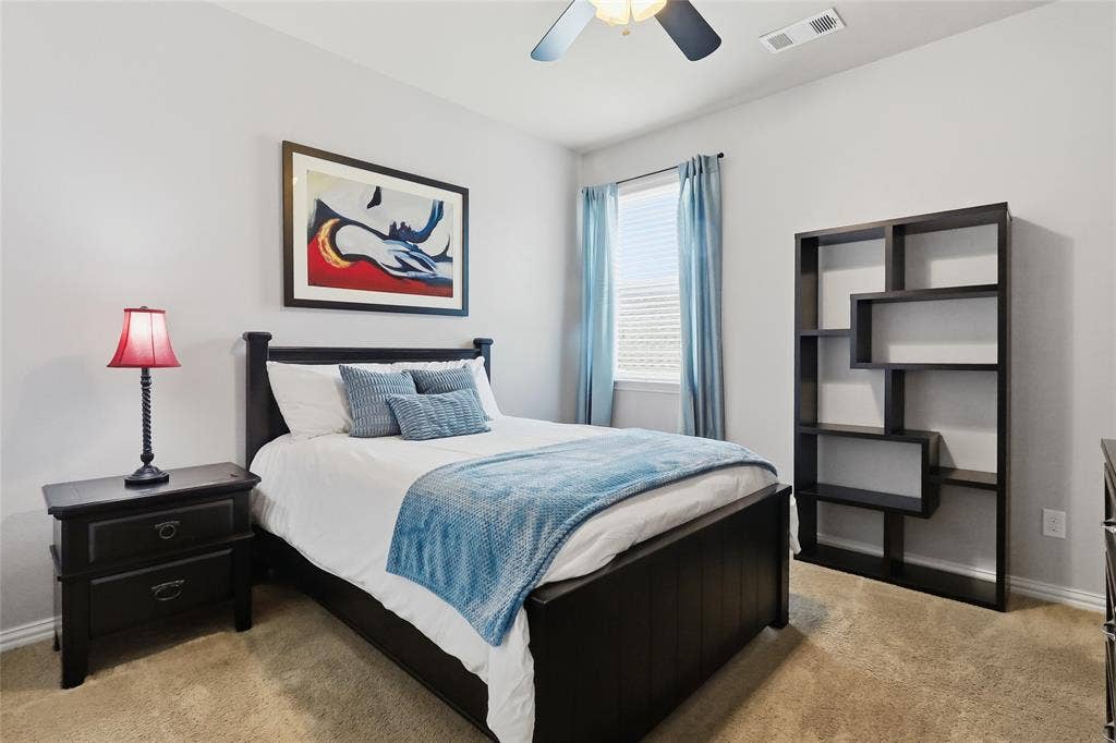 6905 Denali Drive, McKinney, TX 75070 Carpeted room with a ceiling fan, featuring light gray walls and a single window with blinds and blue drapes