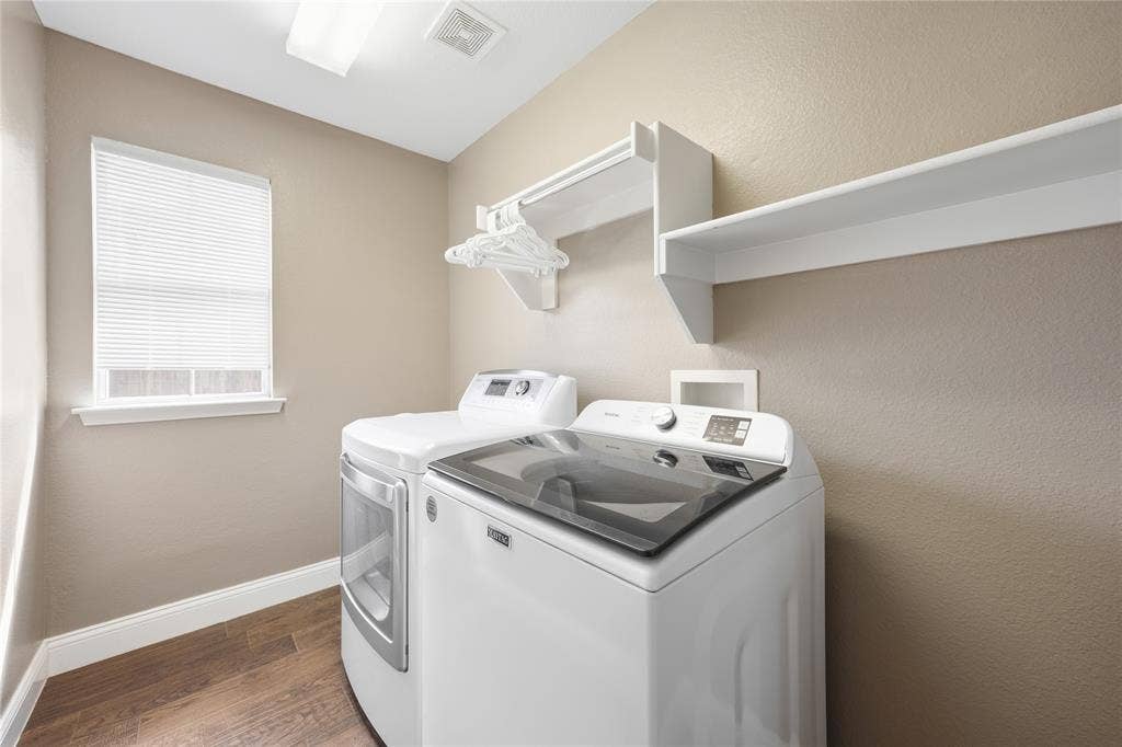 Laundry room featuring wood-finish flooring, a window with blinds, and built-in shelving with a hanging rod